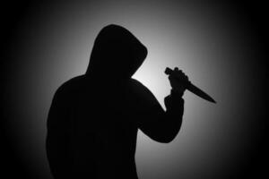 mysterious man wearing black hoodie holding a knife to stab someone crimes and criminality concept photo